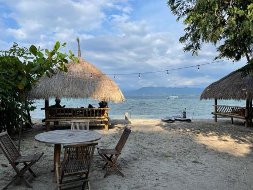 a table and chairs on a beach with the ocean at Tipsea Turtle Gili Air in Gili Air