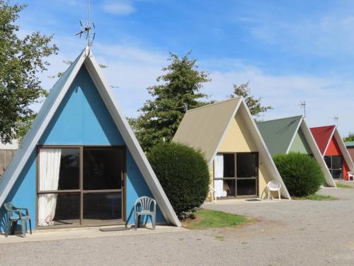 a group of three houses with blue roofs at Rangiora Eco Holiday Park in Fernside
