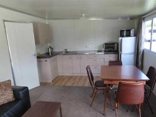 a kitchen and dining room with a table and a refrigerator at Rangiora Eco Holiday Park in Fernside