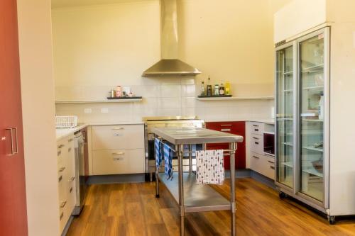 una cocina con armarios blancos y una isla de acero inoxidable en Bellarine Lodge Sleeps 30, en Drysdale