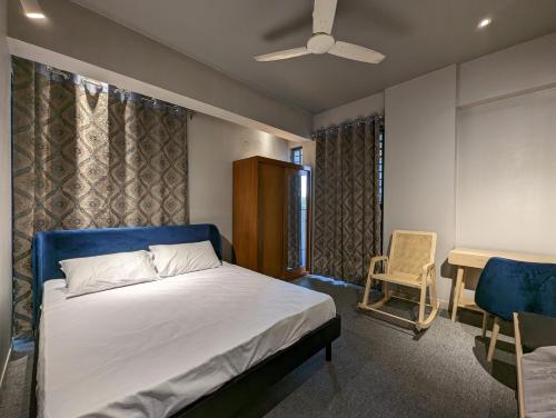 una camera con letto, sedia e ventilatore a soffitto di GreyRooms a Dhaka
