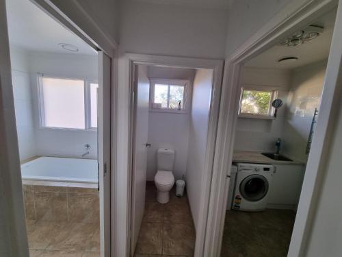 a bathroom with a toilet and a sink and a washing machine at Tussock Sands in Point Lonsdale