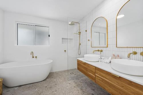 a bathroom with two sinks and a tub and mirror at Luxury home in the heart of Burleigh in Gold Coast