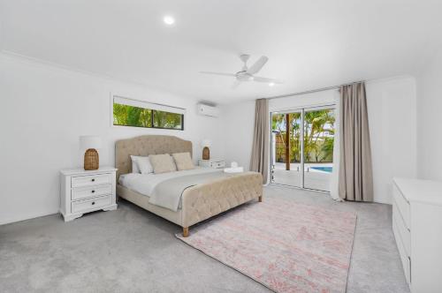 a white bedroom with a bed and a window at Luxury home in the heart of Burleigh in Gold Coast