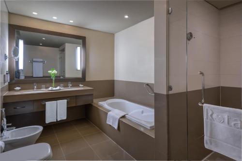 La salle de bains est pourvue d'une baignoire, d'un lavabo et de toilettes. dans l'établissement Park Arjaan by Rotana, Abu Dhabi, à Abu Dhabi
