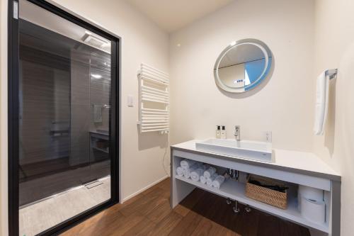 ein Bad mit einem Waschbecken und einem Spiegel in der Unterkunft Le Sauna Villa Hakuba in Hakuba