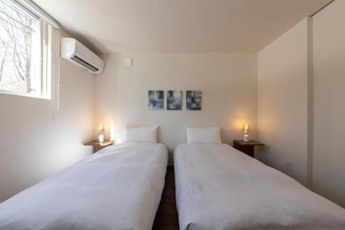 two beds in a room with two lights on the wall at Le Sauna Villa Hakuba in Hakuba