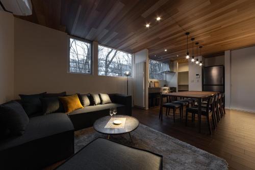 a living room with a couch and a table at Le Sauna Villa Hakuba by JAMSZ ROYALE in Hakuba