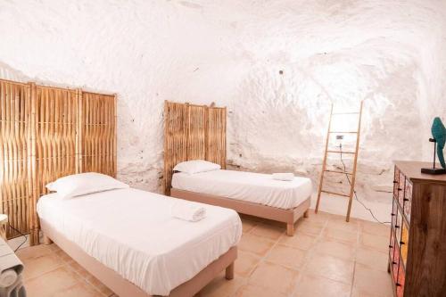 Un dormitorio con 2 camas y una escalera. en Maison troglodyte - Le Cerisier Perché en Luynes