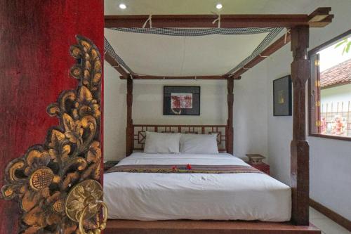 a bedroom with a bed with a wooden canopy at Rumah Paros & Gallery in Sukawati