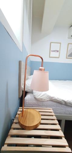lampa siedząca na ławce obok łóżka w obiekcie One Minute Guesthouse w Seulu