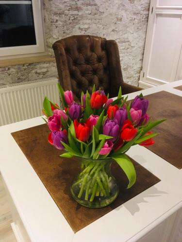 a vase of flowers on a table with a chair at Hotel Haus Loewe in Frechen