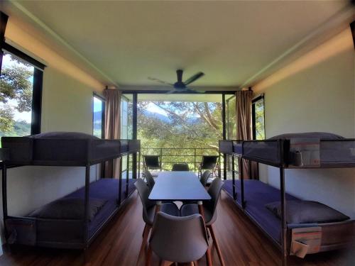 a room with three bunk beds and a table and chairs at The Hill in Kampong Sum Sum