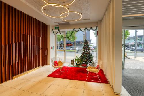 a christmas tree in a hallway with chairs and a red rug at Ramada by Wyndham, Hamilton City Center in Hamilton