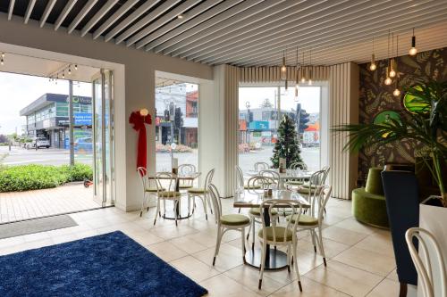 a dining room with tables and chairs and windows at Ramada by Wyndham, Hamilton City Center in Hamilton