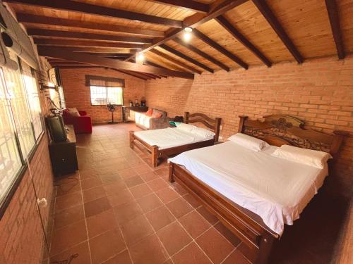 1 dormitorio con 2 camas en una pared de ladrillo en Finca Villa Melita, Privada en Piedecuesta, en Piedecuesta