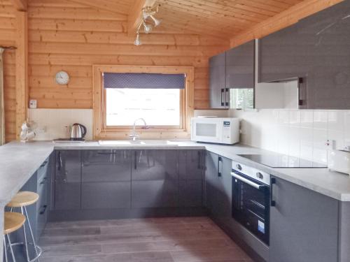 a kitchen with gray cabinets and a sink and a window at Paradise Lodge-uk31996 in Legbourne