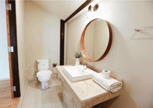 a bathroom with a sink and a toilet and a mirror at Khaoyai Valley1 บ้านพักเขาใหญ่วัลเล่ย์1 in Mu Si