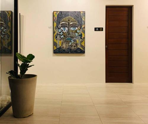 une plante en pot dans une pièce avec une peinture sur le mur dans l'établissement The Great Molave DELUXE ROOM, à Cavite