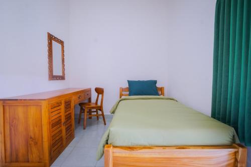 a bedroom with a bed and a desk and a chair at Kos Bulan Bali in Kuta