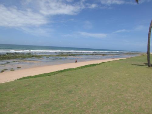 a person walking on a beach with the ocean at Pousada Ipitanga IV in Lauro de Freitas