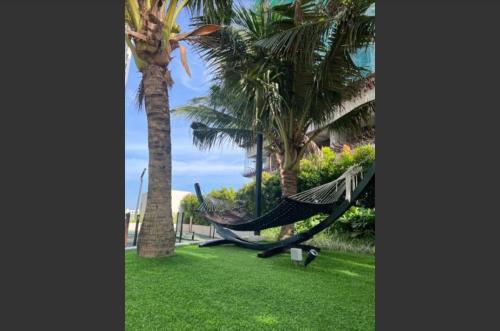 a hammock in a park with palm trees at bali residensi in Melaka