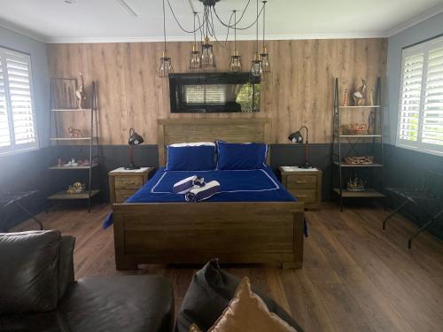 1 dormitorio con cama con sábanas azules y sofá en Mahalo BnB, en Mapleton