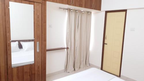 een kamer met een kast en een deur met een spiegel bij Chippy Apartments No.544 in Chennai