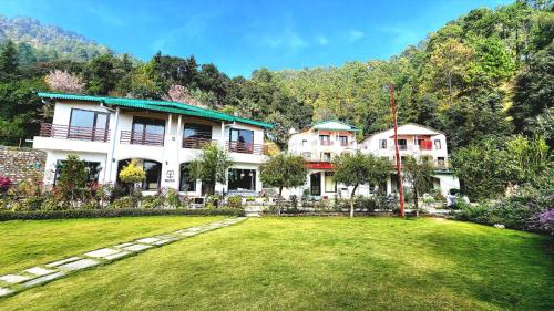 Just Naturals Wellness Resort Nainital في Bhowāli: منزل كبير مع حديقة أمامه