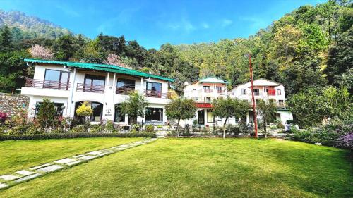 a large house with a lawn in front of it at Just Naturals Wellness Resort Nainital in Bhowāli