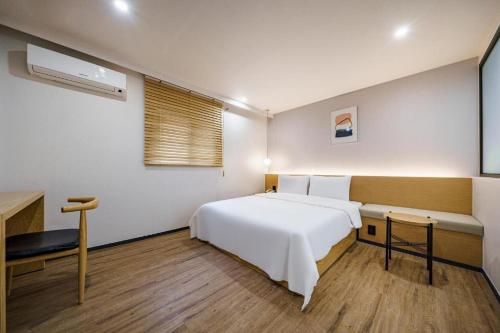 a bedroom with a large white bed and a desk at Hotel Yaja Changwon Myeongseo in Changwon