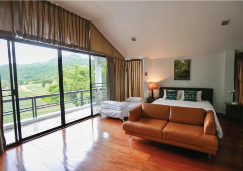 a bedroom with a bed and a couch and a balcony at Khaoyai Valley1 บ้านพักเขาใหญ่วัลเล่ย์1 in Mu Si