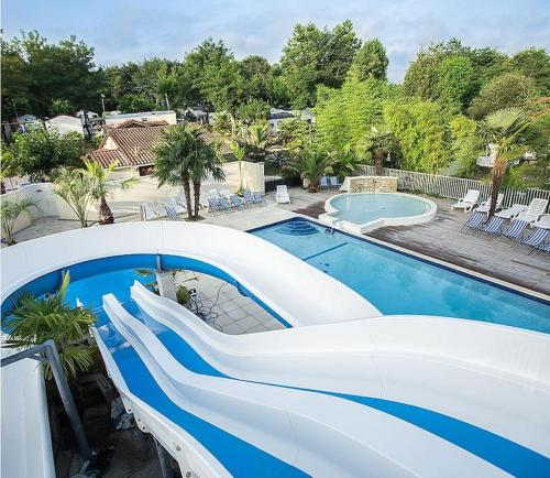 - une piscine avec toboggan à côté d'une maison dans l'établissement Chalet à louer - 52m2 - Landes, à Saint-Geours-de-Maremne