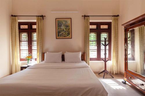 um quarto com uma cama grande e 2 janelas em StayVista at Crystal Homestay with Breakfast & Bicycle em Madikeri