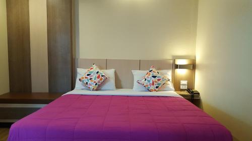 Kaen Nakorn Hotel في كون كاين: غرفة نوم بسرير ارجواني مع وسادتين