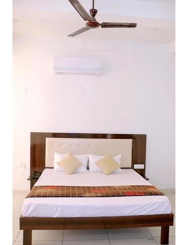 a bed with white sheets and a ceiling fan at Hotel UV, Haryana in Nārnaul