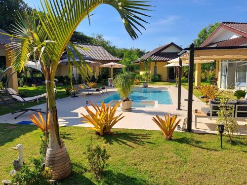 a palm tree in a yard next to a pool at Pool Villa, Resort, Mae Ramphueng Beach, Ban Phe, Rayong, Residence M Thailand in Ban Chamrung