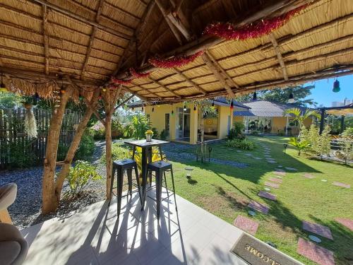 a patio with two stools under a wooden pergola at Residence M Thailand, Resort, Mae Ramphueng Beach, Ban Phe, Rayong, Residence M Thailand in Ban Chamrung