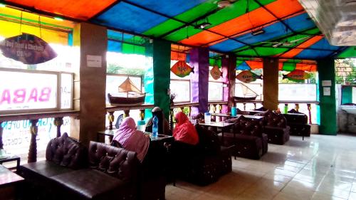 two people sitting in a restaurant with colorful ceilings at Baba Lao Hotel in Malindi