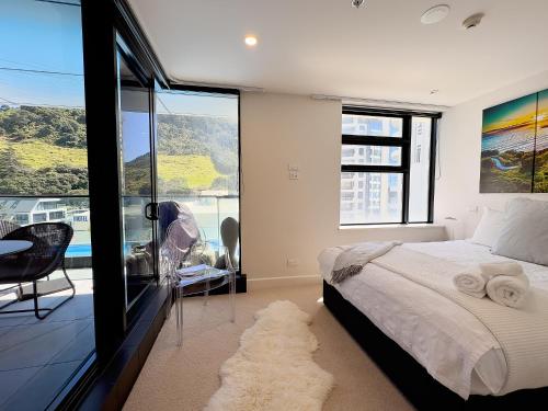 a bedroom with a bed and a balcony with a view at Mt Maunganui Main Beach Luxury with Seaviews in Tauranga