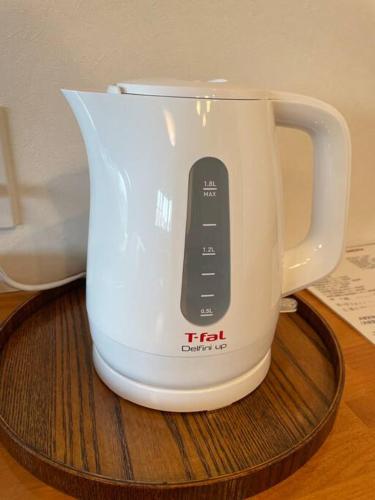 a white tea kettle with a remote control on a coaster at 雅 南熱海 温泉別荘 Ocean View Hotspring Villa in Ajiro