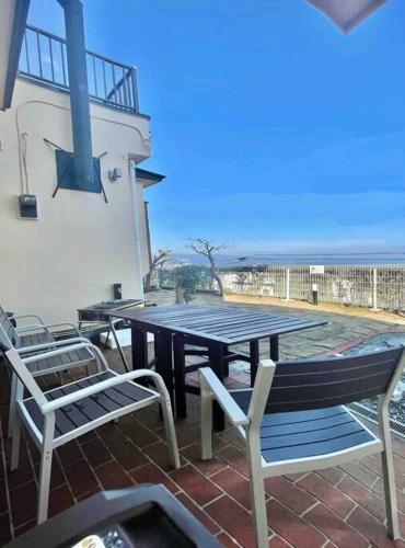 a picnic table and chairs on a patio with the ocean at 雅 南熱海 温泉別荘 Ocean View Hotspring Villa in Ajiro