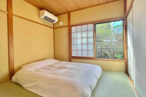 a small bedroom with a bed and a window at 雅 南熱海 温泉別荘 Ocean View Hotspring Villa in Ajiro