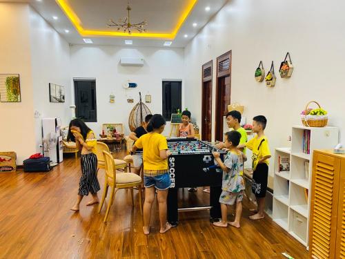 een groep kinderen die spelen met een tafel in een kamer bij LaLi Home in Hanoi