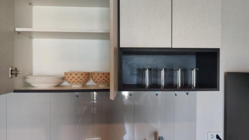 a kitchen with white cabinets and bowls on a shelf at Many Holiday The Base Condo in Pattaya Central