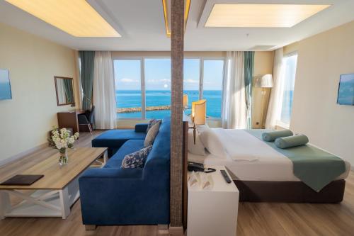 トラブゾンにあるティルヤ リゾート ホテルの大きなベッドと青いソファが備わるホテルルームです。