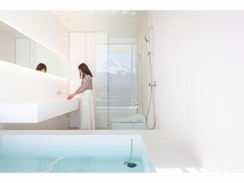 富士河口湖的住宿－THE GARDEN，站在带水槽的浴室中的女人