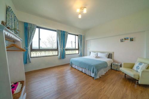 1 dormitorio con 1 cama, 1 silla y ventanas en Cathy French House, en Dongshan