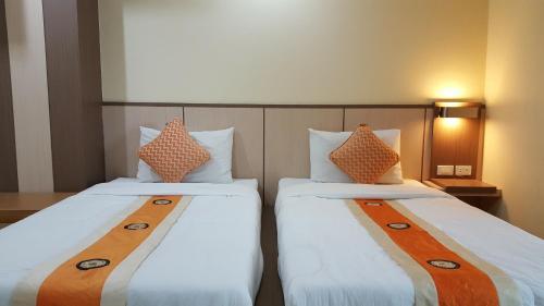 2 Betten nebeneinander in einem Zimmer in der Unterkunft Kaen Nakorn Hotel in Khon Kaen