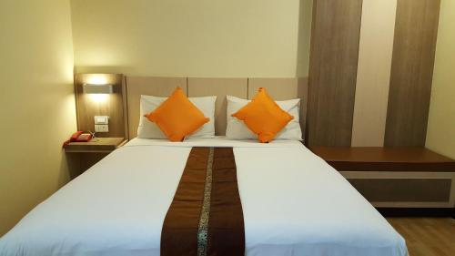 Kaen Nakorn Hotel في كون كاين: غرفة نوم مع سرير كبير مع وسائد برتقالية